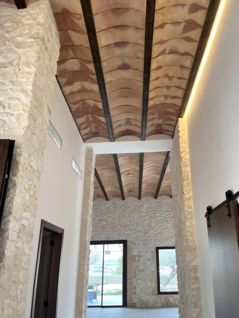 Pasillo con forjado con vigas vistas de hormigón imitación madera.